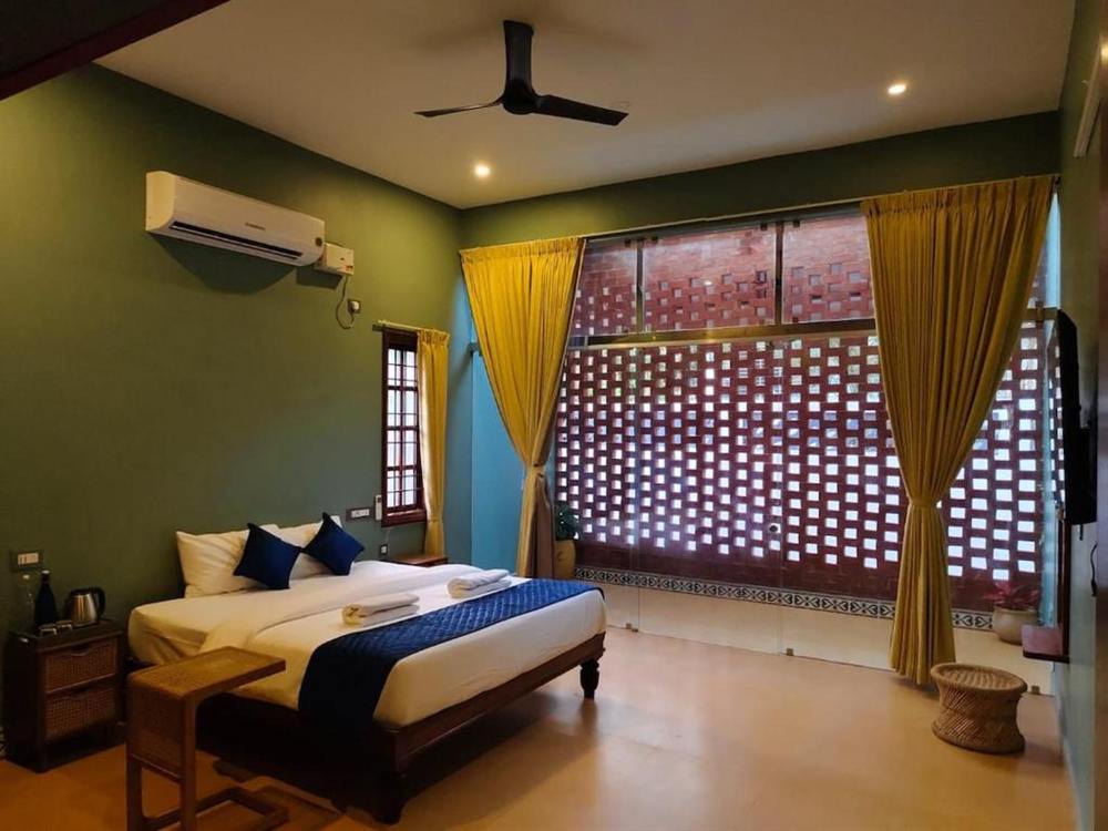 Superior Villa bedroom with green walls, mustard curtains and a terracotta jaali screen window